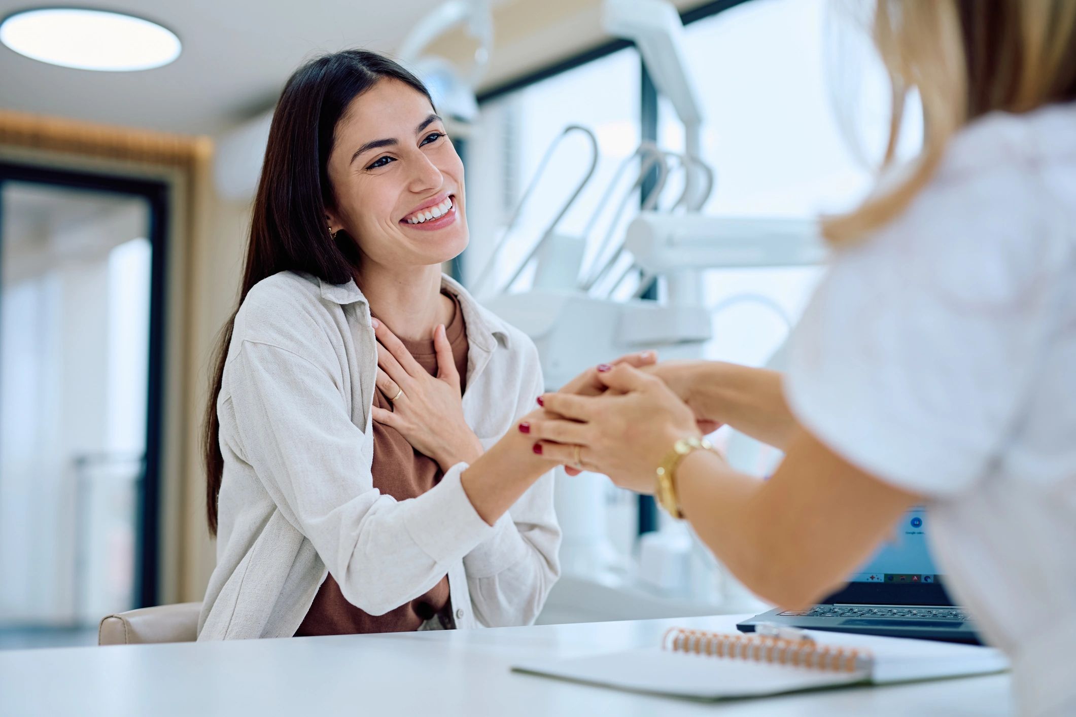 Patient gratefully holding hands with her dentist after treatment